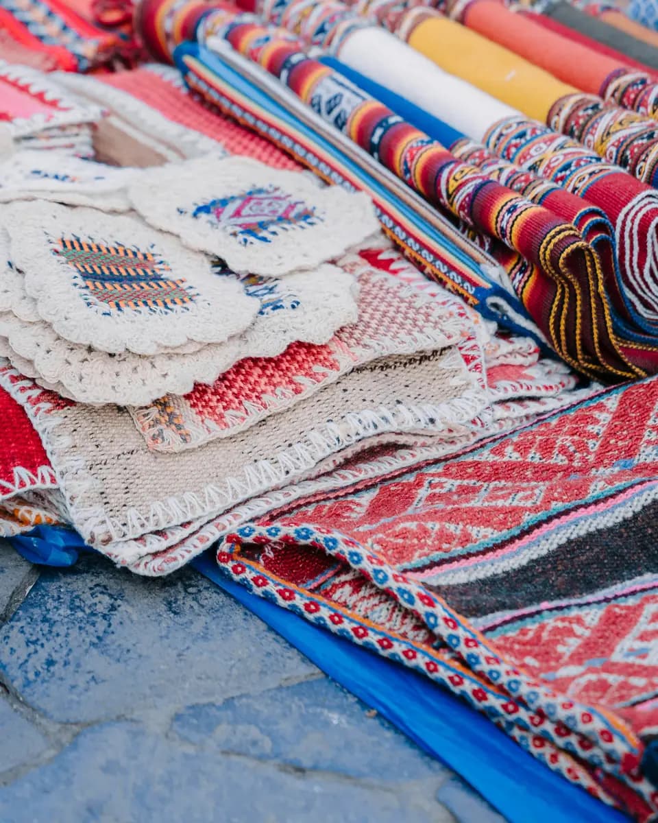 Colorful woven textiles and handmade pieces arranged at a market in Cusco.