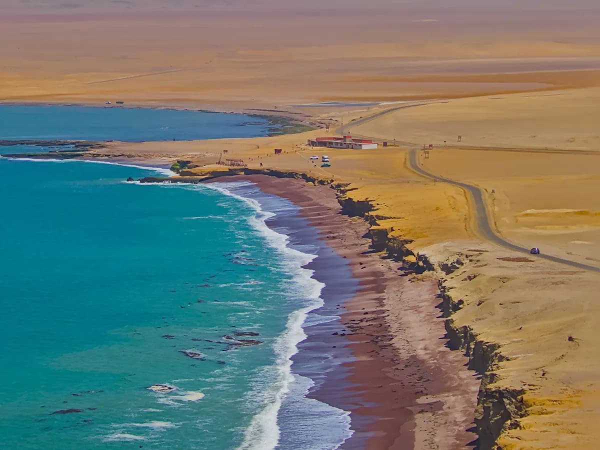 Golden coastal desert beside turquoise ocean water in Peru.